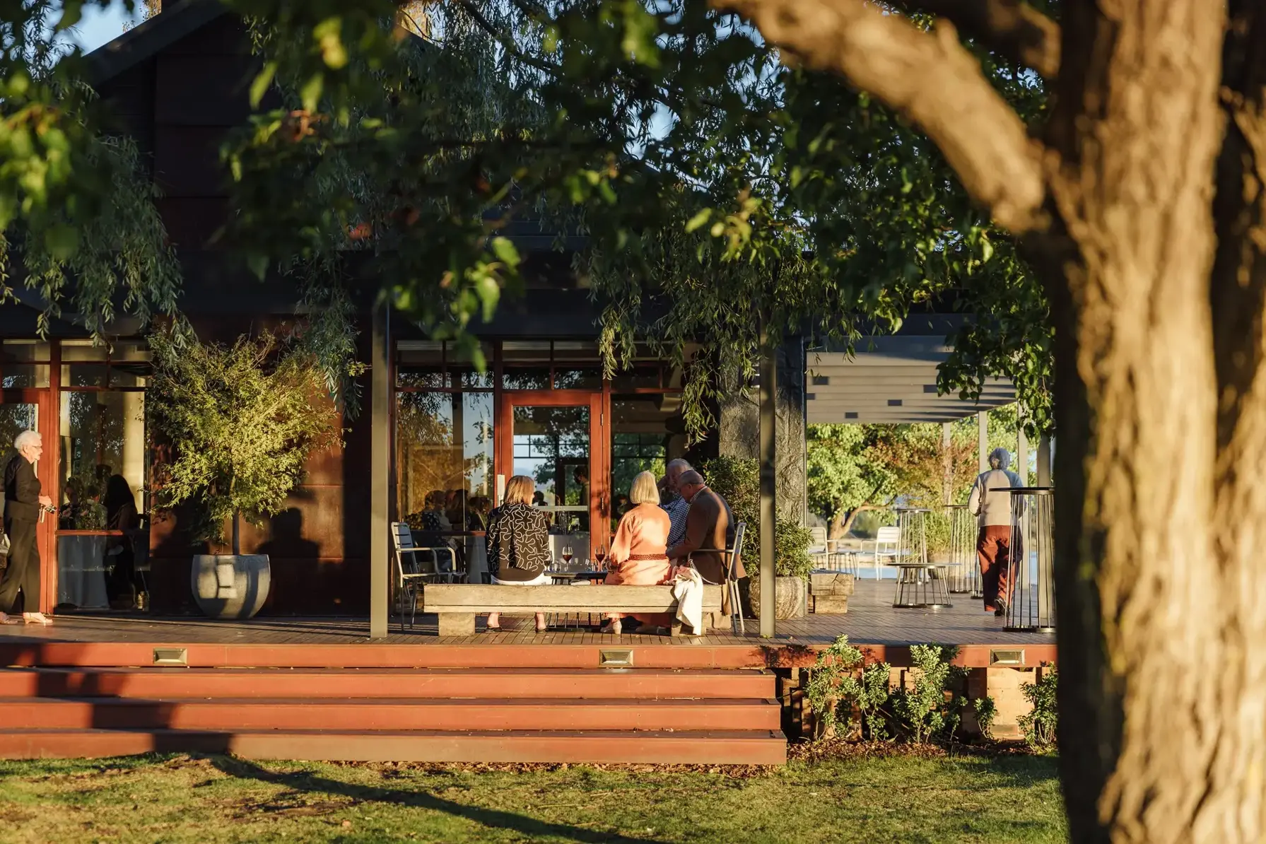 Guests seated on the timber deck outside The Boat House in Barton